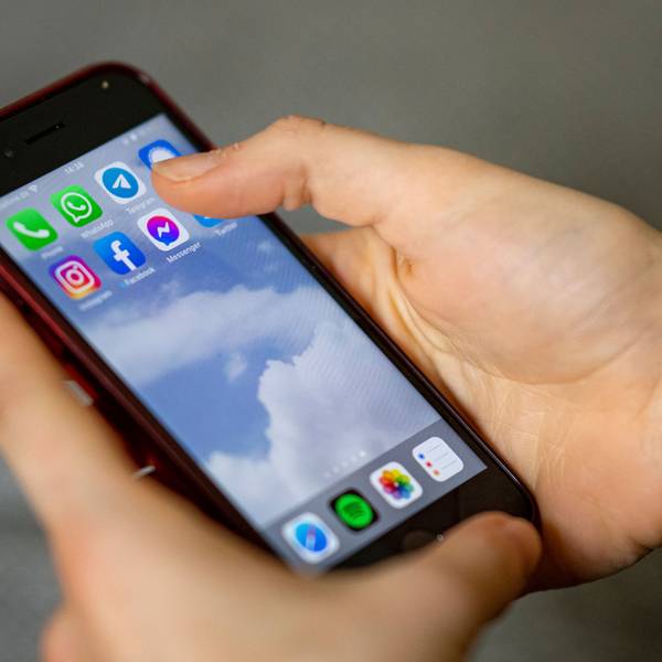 Auf dem Bildschirm eines Smartphones, das eine Person in der Hand hält, sieht man die Symbole verschiedener sozialer Medien und Messenger-Dienste.