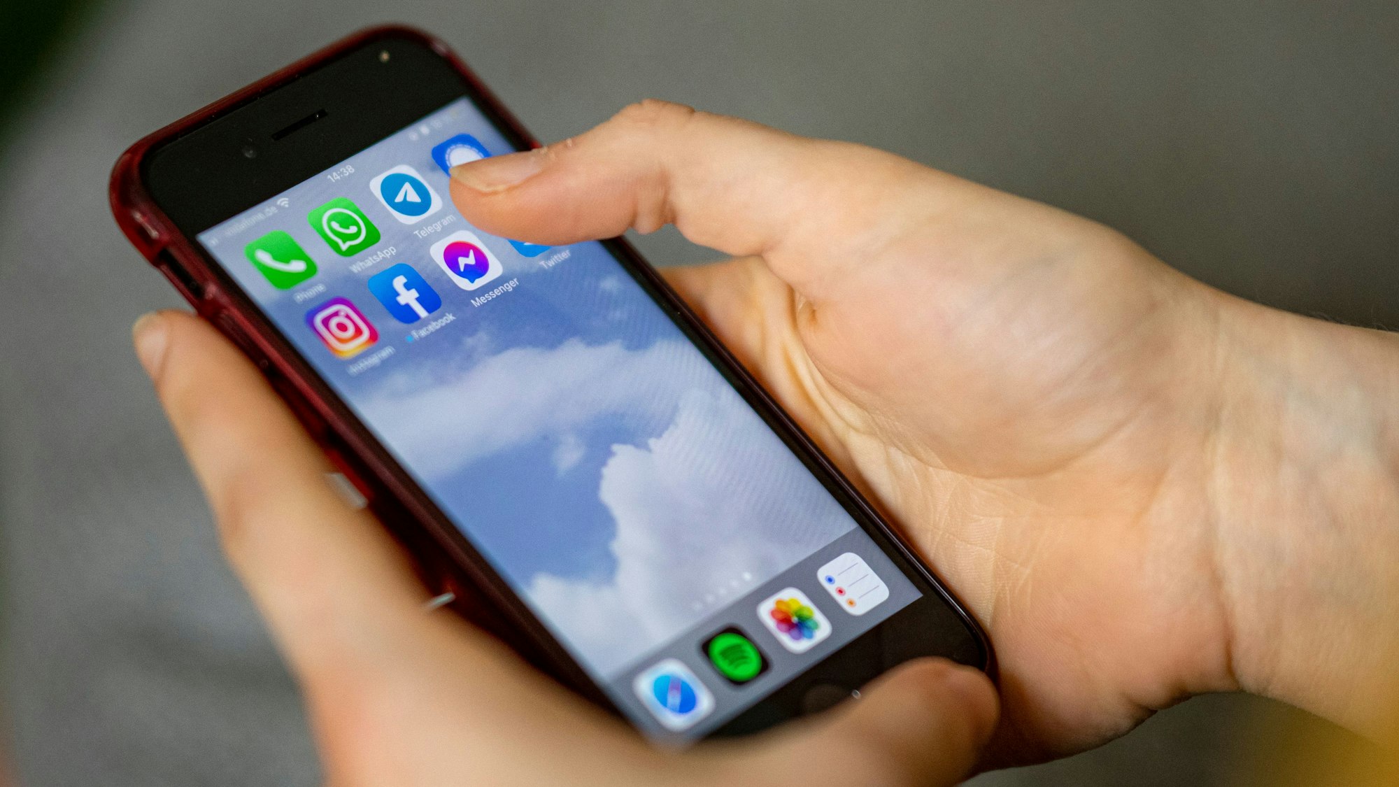 Auf dem Bildschirm eines Smartphones, das eine Person in der Hand hält, sieht man die Symbole verschiedener sozialer Medien und Messenger-Dienste.