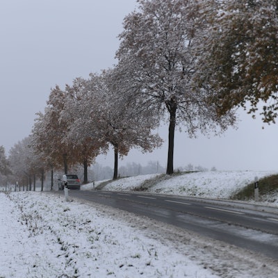 Neben einer Landstraße im Rhein-Seig-Kreis sind die umliegenden Wiesen mit Schnee bedeckt.