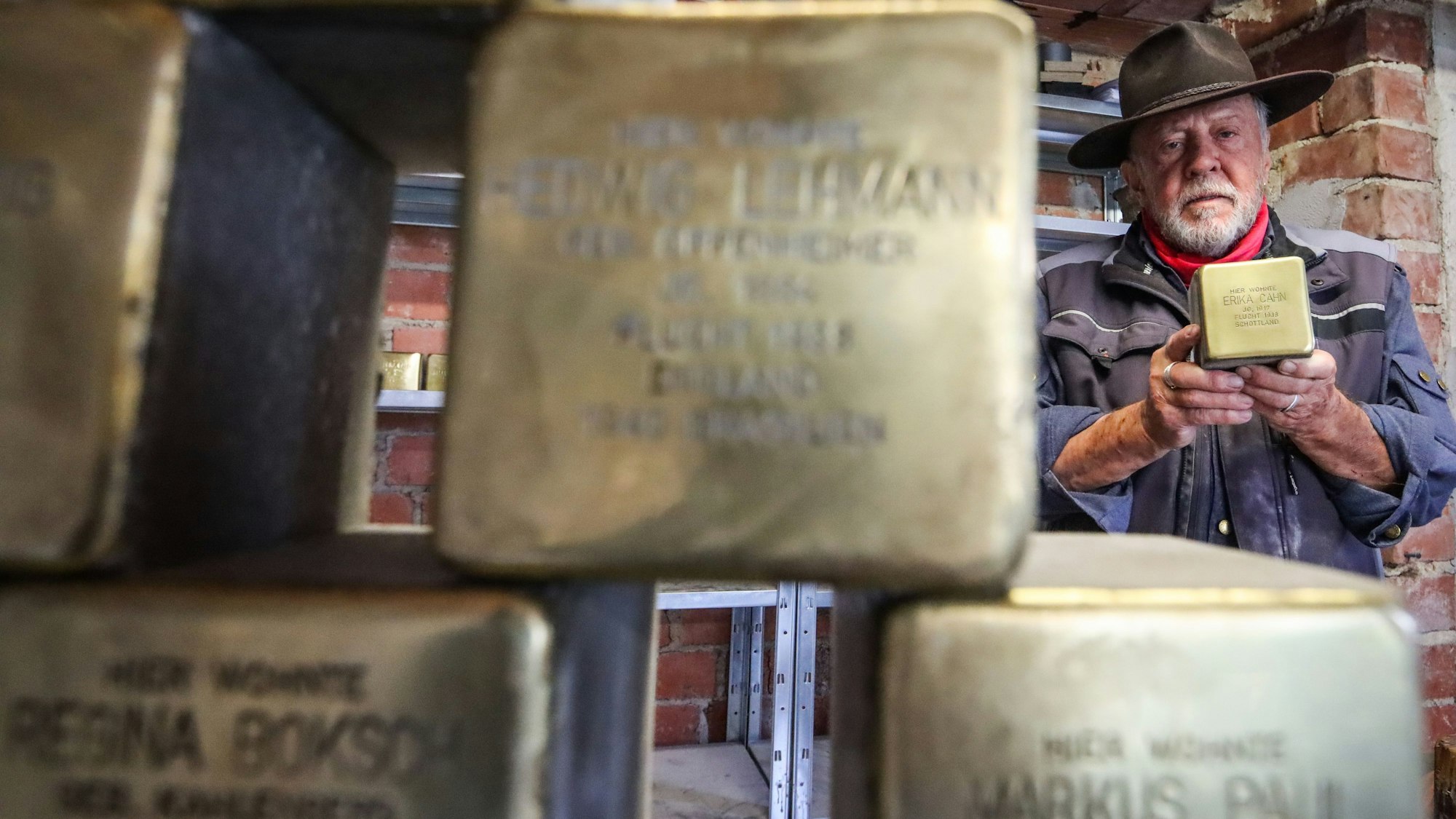 Künstler Gunter Demnig hält einen seiner Stolpersteine in der Hand.