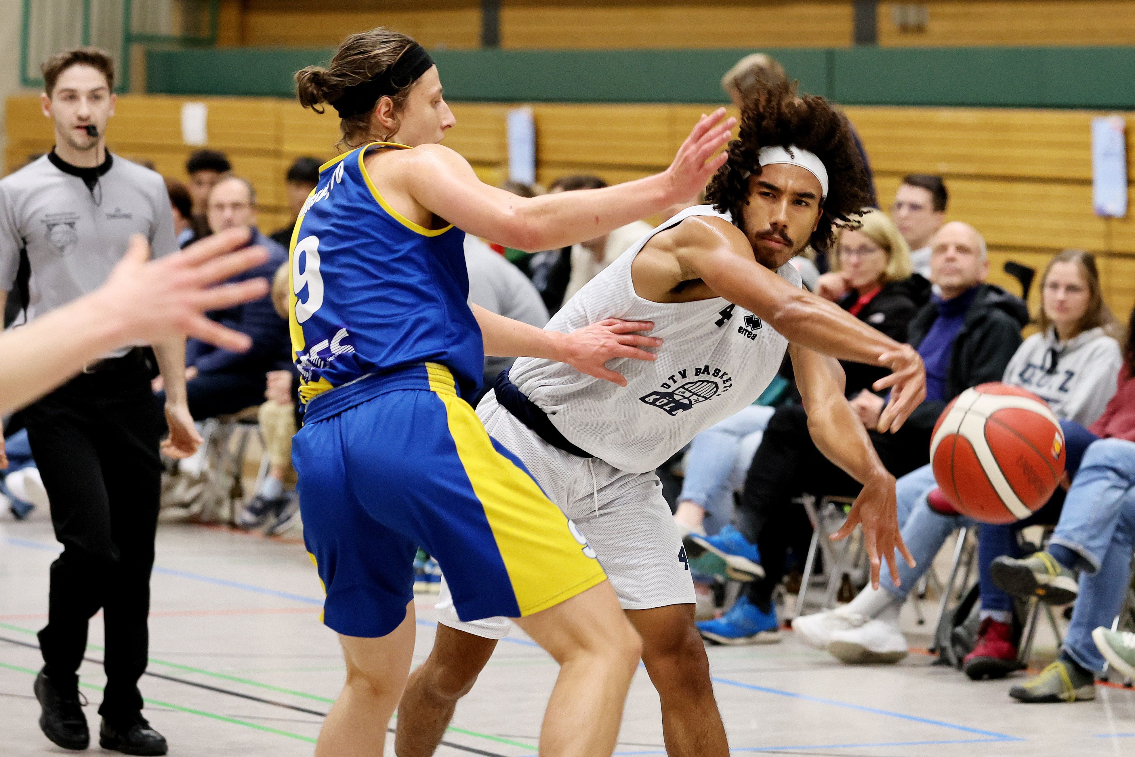 Ein Basketballer passt den Ball an seinem Gegenspieler vorbei.