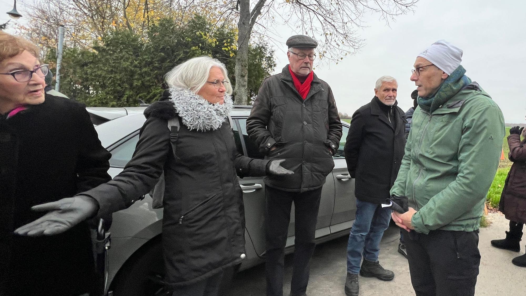 Fünf Menschen stehen in einer Gruppe zusammen. Eine Frau, Monika Thole, diskutiert mit ausgebreiteten Armen mit Jörg Lichter, der vor ihr steht.