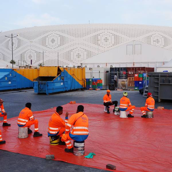 Arbeiter sitzen außerhalb eines Stadions in Doha, das für die Fußball-Weltmeisterschaft 2022 gebaut wurde.