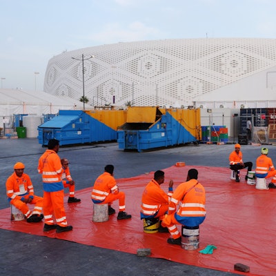 Arbeiter sitzen außerhalb eines Stadions in Doha, das für die Fußball-Weltmeisterschaft 2022 gebaut wurde.