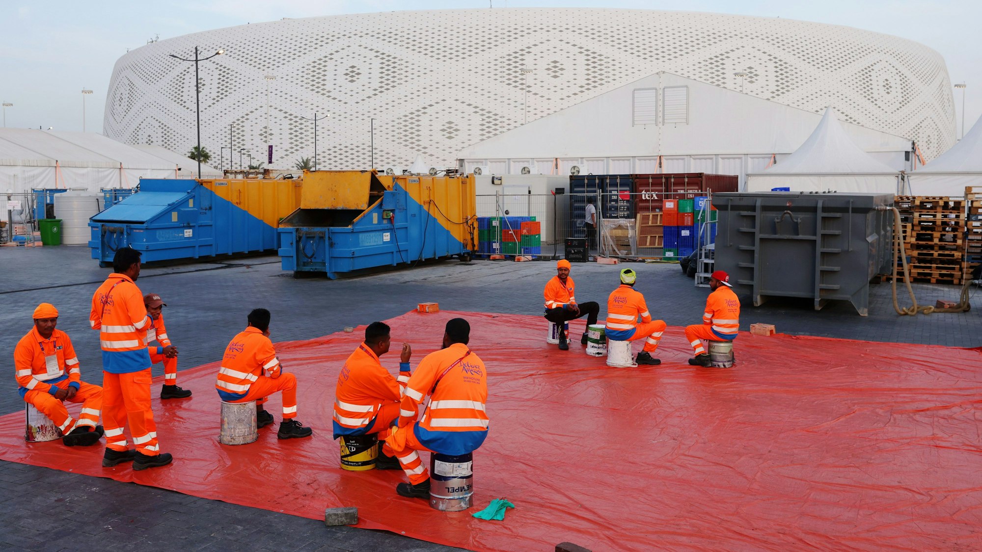Arbeiter sitzen außerhalb eines Stadions in Doha, das für die Fußball-Weltmeisterschaft 2022 gebaut wurde.