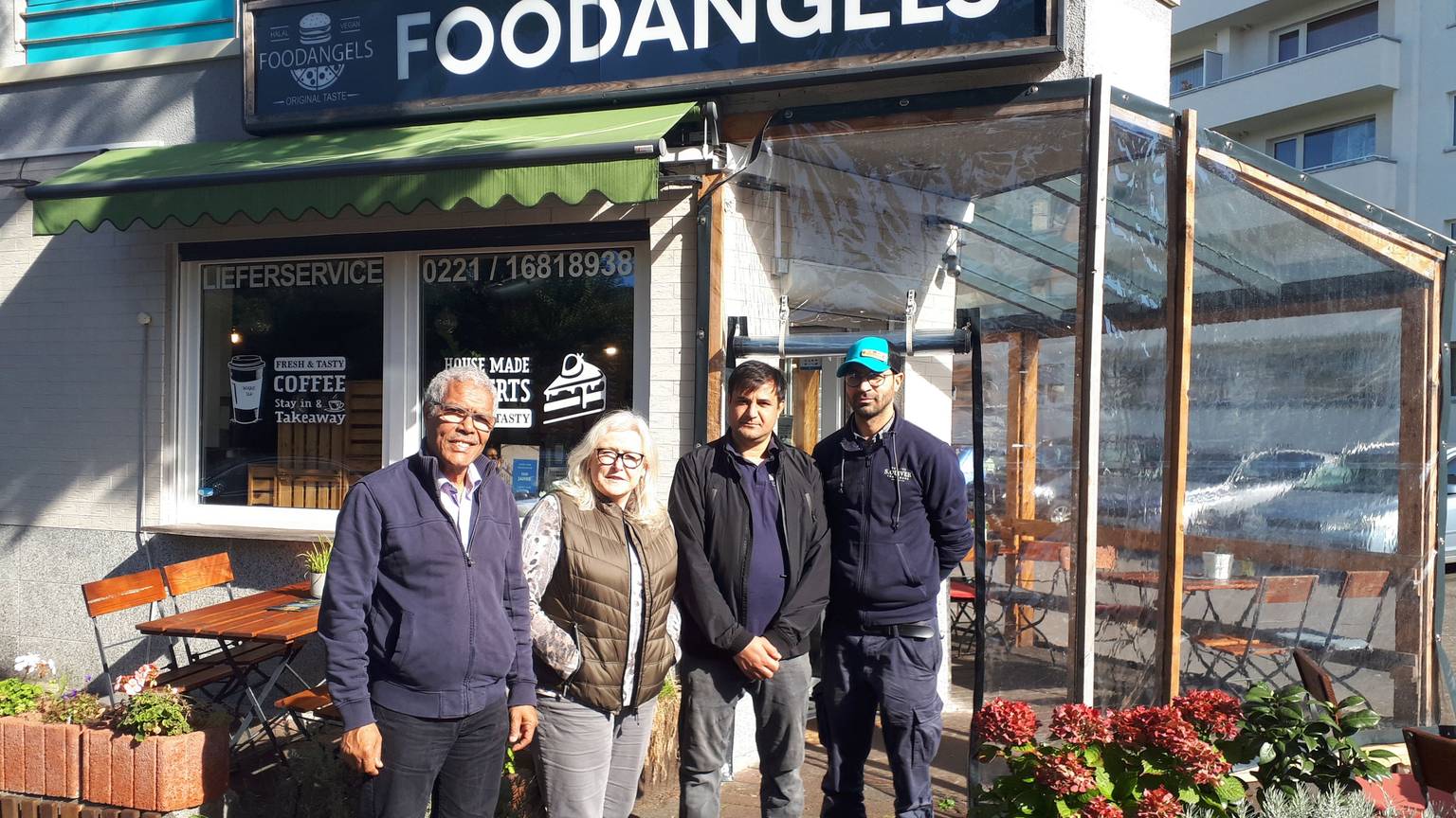 Najib Ramz, Susanna Zeltinger, der betroffene Fazal Rabi Rahimzai und 'Foodangels'-Betreiber Mazlom Sediqi stehen vor dem Restaurant „Foodangels“ in Köln.