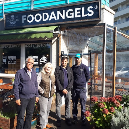 Najib Ramz, Susanna Zeltinger, der betroffene Fazal Rabi Rahimzai und 'Foodangels'-Betreiber Mazlom Sediqi stehen vor dem Restaurant „Foodangels“ in Köln.