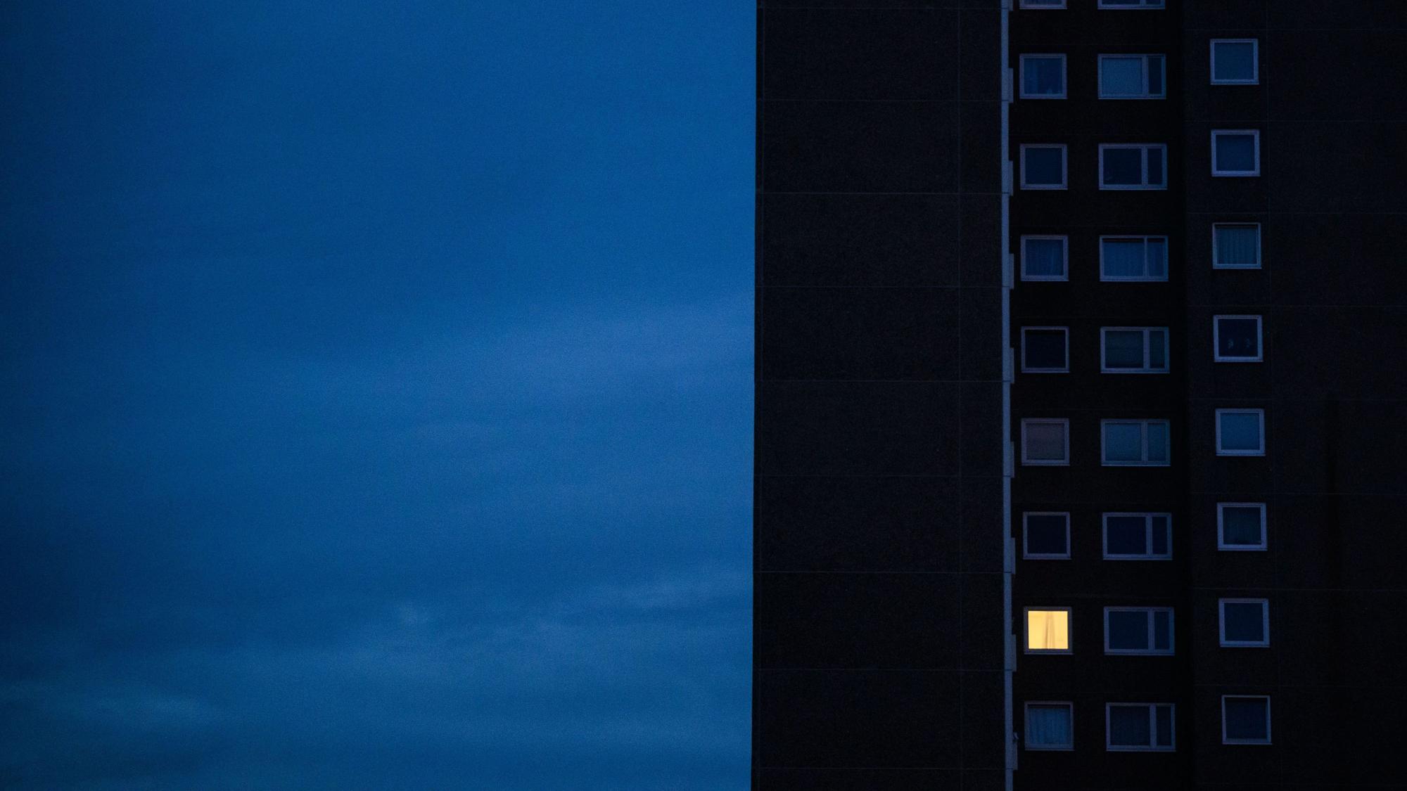 Nur in einer Wohnung eines Hochhauses brennt am frühen Morgen Licht.
