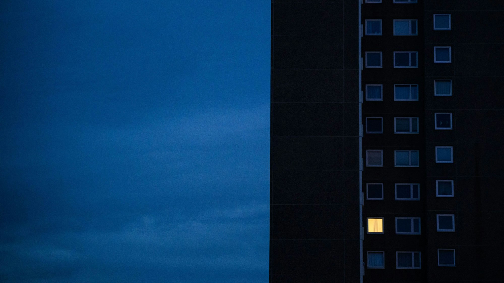 Nur in einer Wohnung eines Hochhauses brennt am frühen Morgen Licht.