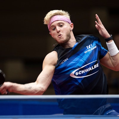 Zu sehen ist ein junger Tischtennisspieler, der den Ball mit der Vorhand über das Netz schlägt.