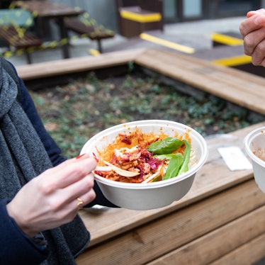 Ein Mann und eine Frau nehmen ihr Mittagessen aus einer Einwegverpackung zu sich.