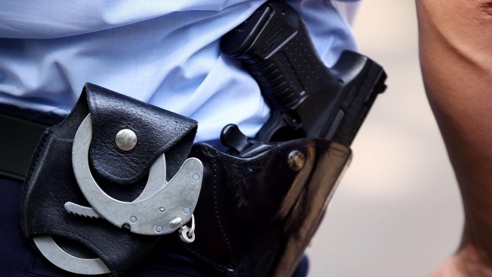 Ein Polizist mit Handschellen und Pistole am Gürtel in Köln: Am Samstagabend (5. Oktober/2024) schoss ein 48-Jähriger in einer Kölner Gaststätte offenbar auf einen 35-Jährigen.