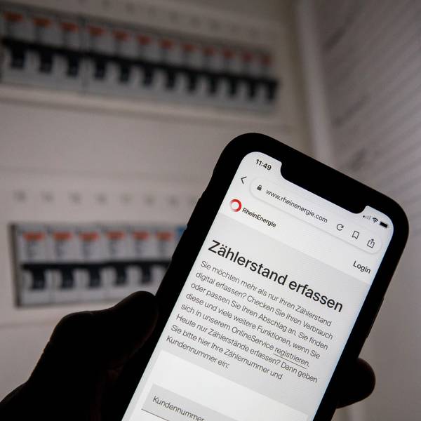 Eine Webseite der Rhein-Energie zur Erfassung des Zählerstands ist vor einem geöffneten Sicherungskasten zu sehen.