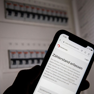 Eine Webseite der Rhein-Energie zur Erfassung des Zählerstands ist vor einem geöffneten Sicherungskasten zu sehen.