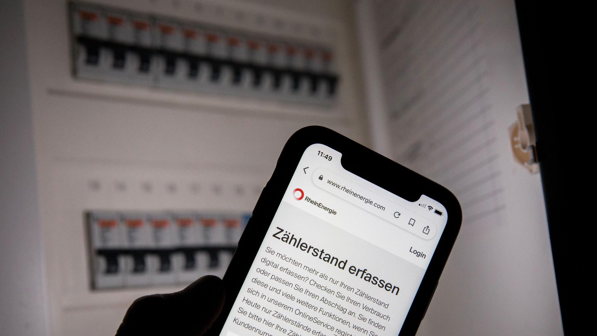Eine Webseite der Rhein-Energie zur Erfassung des Zählerstands ist vor einem geöffneten Sicherungskasten zu sehen.