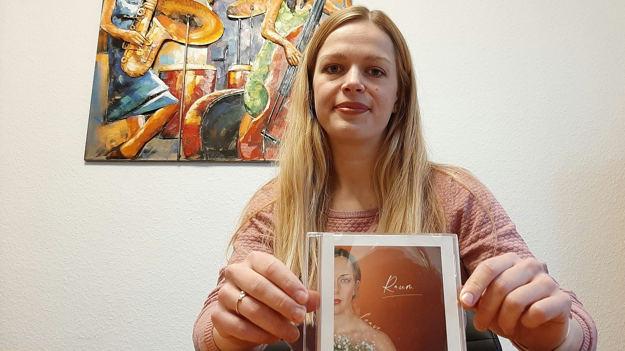 Die Leverkusenerin Lea Sauter sitzt in ihrer Wohnung und zeigt das Cover zu ihrem Song „Raum“.