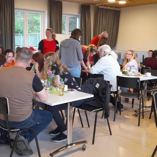 Café International des Fluchtpunkts Kürten: An mehreren längeren Tischen sitzen Menschen verschiedener Nationen und unterhalten sich.