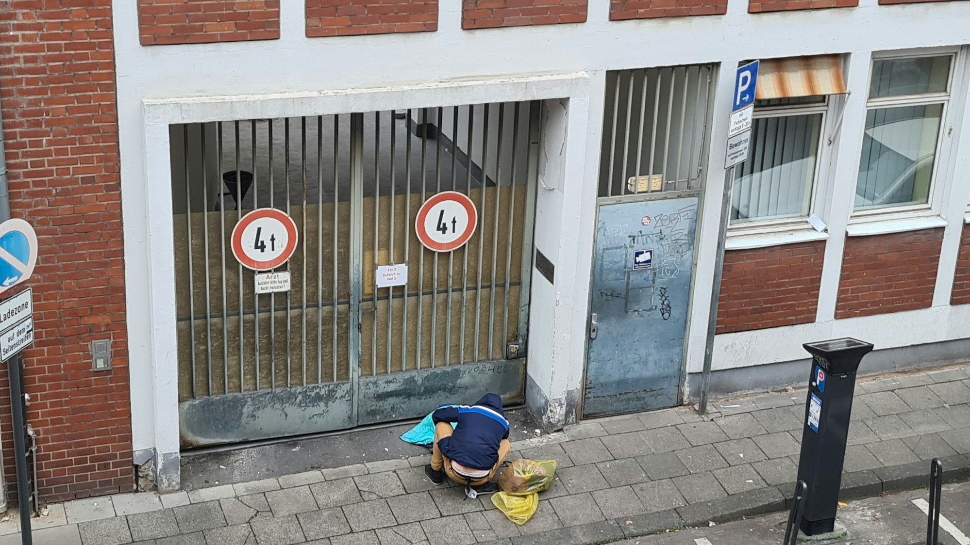 Ein abhängiger Mann sitzt in der Lungengasse vor der verschlossenen Tür des Drogenkonsumraums.