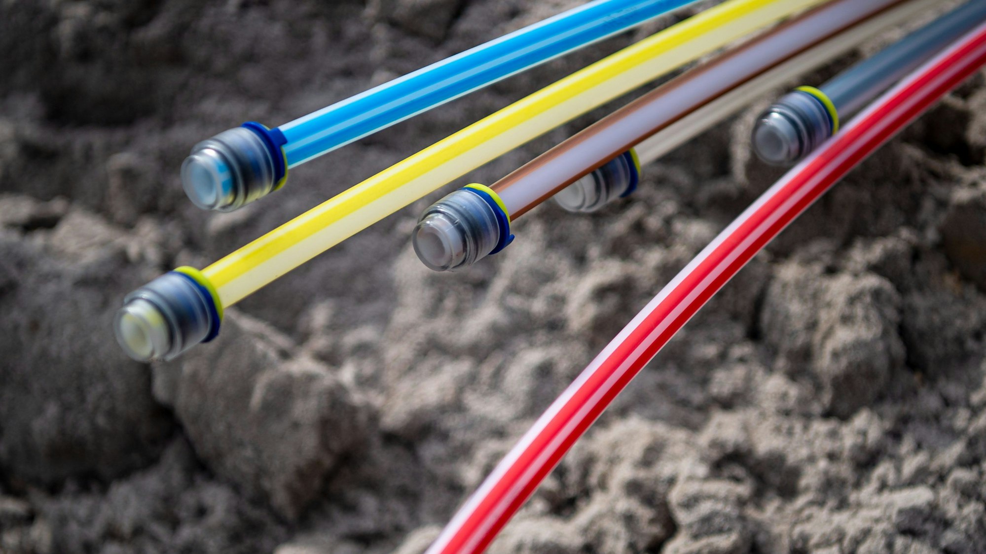 Verschiedenfarbige Kabel liegen auf Geröll.