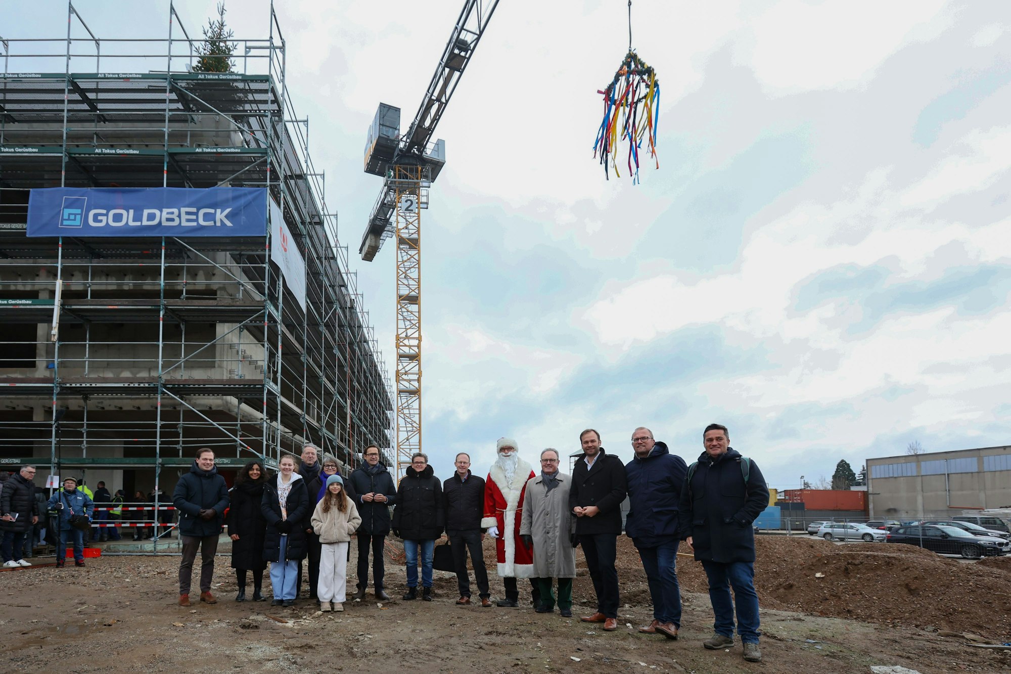Die Gäste des Richtfestes auf der Baustelle, hinter ihnen ein Kran.
