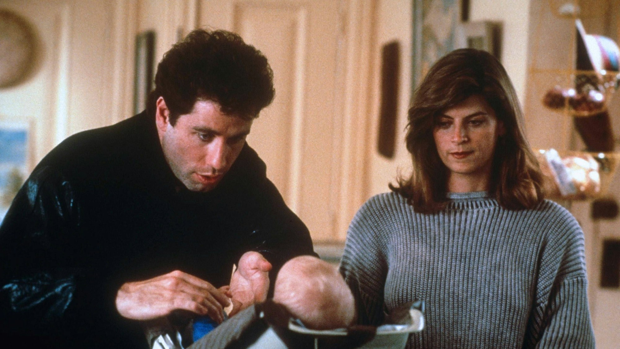 John Travolta und Kirstie Alley mit Baby in der Küche.