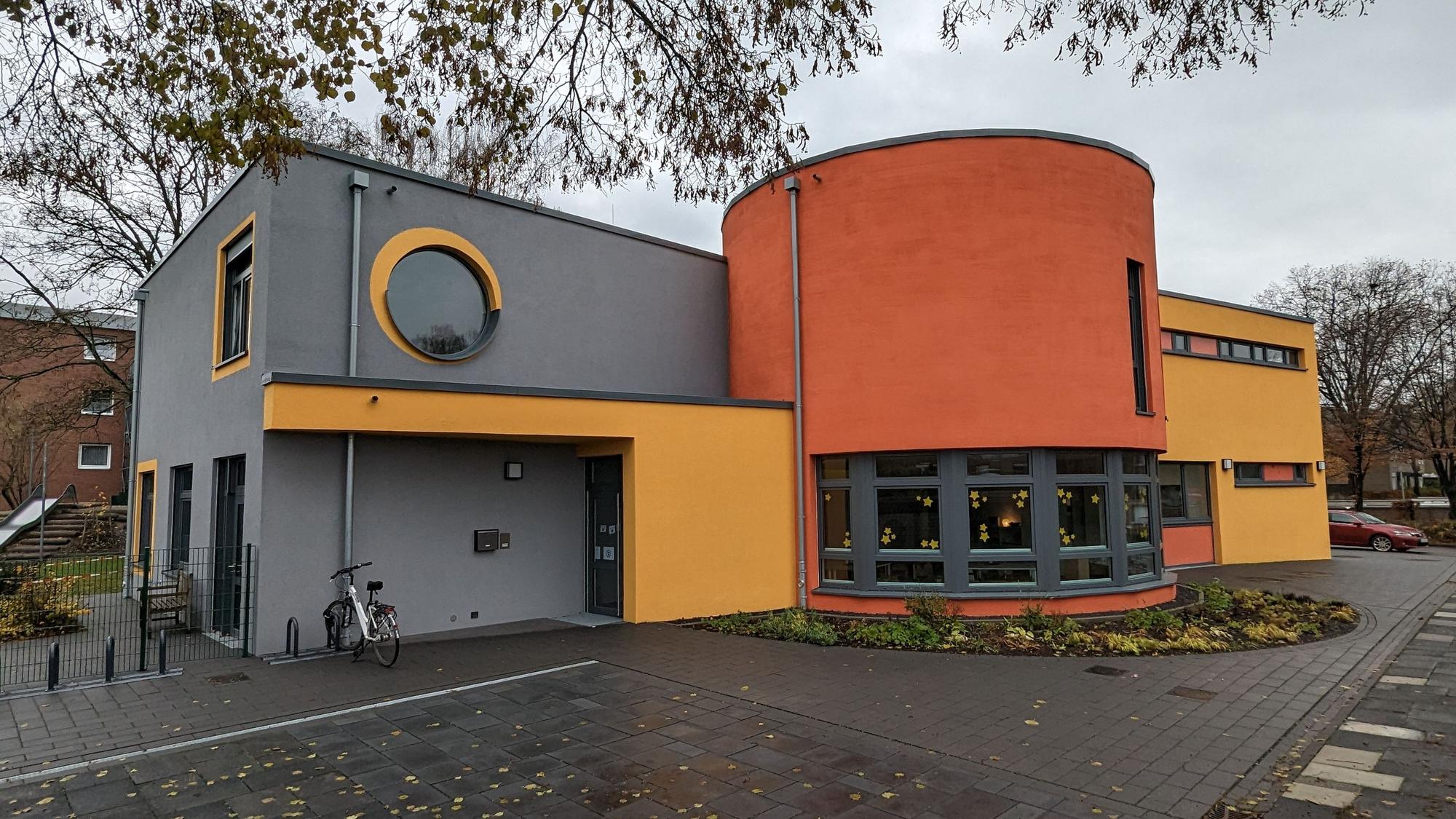 Ein Kita-Gebäude mit grau, gelb und orangen Außenwandfarben.