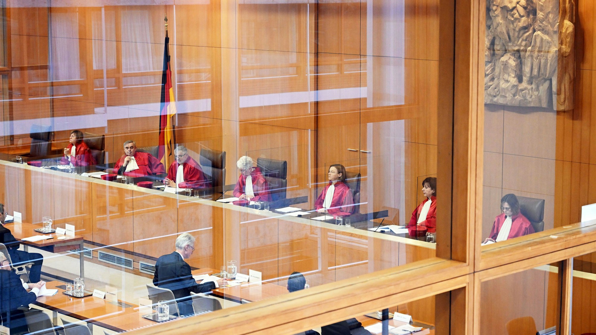Der Zweite Senat des Bundesverfassungsgericht, (l-r) Astrid Wallrabenstein, Peter Müller, Peter M. Huber, Doris König (Vorsitz), Monika Hermanns, Sibylle Kessal-Wulf und Christine Langenfeld, verkündet das Urteil zu milliardenschweren EU-Corona-Fonds. Sie sind durch eine Scheibe fotografiert.
