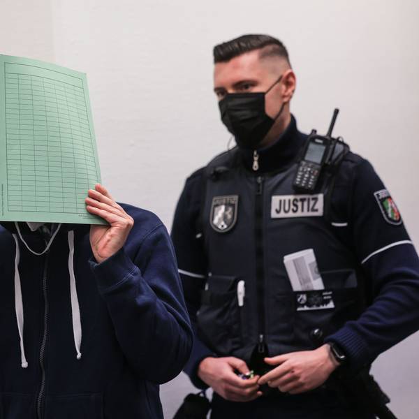 Der Angeklagte (M) im Missbrauchskomplex Wermelskirchen hält sich beim Betreten des Gerichtssaals neben seinem Rechtsanwalt Christian Lange (l) eine Mappe vor das Gesicht. Der Mann soll sich im Internet als Babysitter angeboten und so Kontakt zu den Familien der Opfer bekommen haben. Insgesamt ist er wegen 124 Taten angeklagt, darunter auch Besitz von Kinderpornografie und Beihilfe zum Missbrauch.