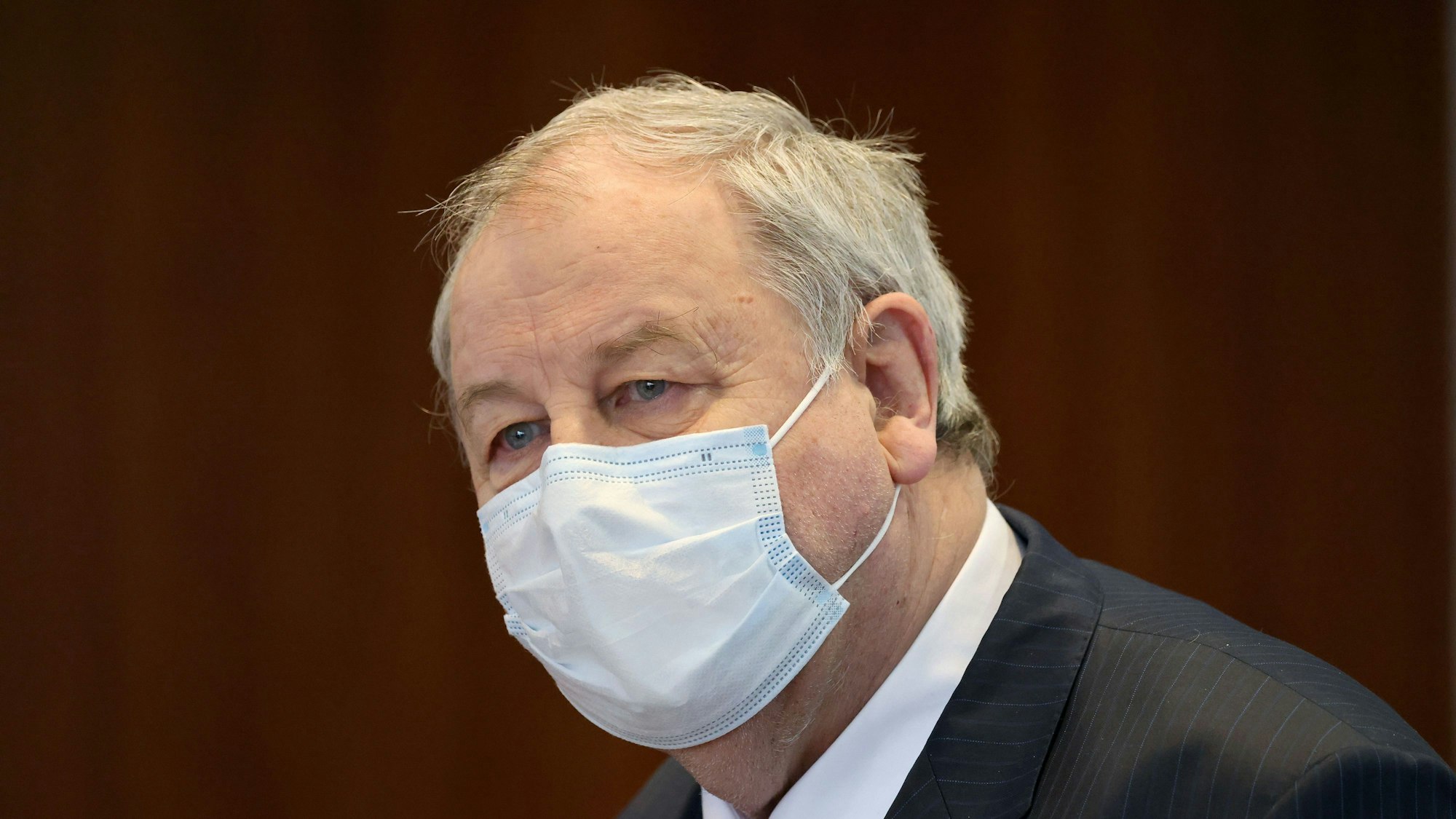 Hanno Berger, Angeklagter, steht im Gerichtssaal. Er trägt einen Mund-Nasen-Schutz und schaut an der Kamera vorbei.