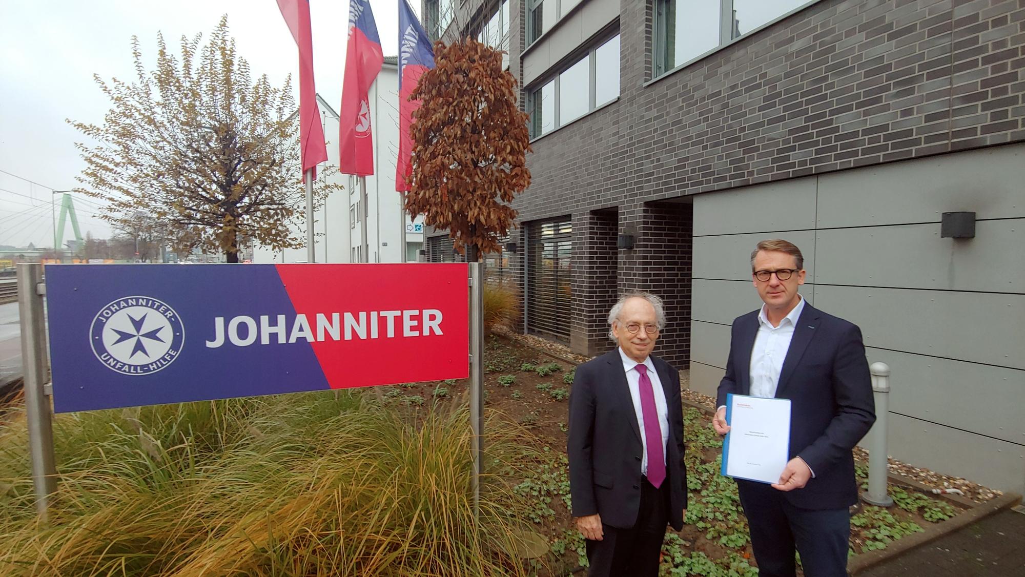 Verfasser Micha Guttmann (l.) und Johanniter-Regionalvorstand Marius Mainzer (r.) stehen vor der Landesgeschäftsstelle NRW des Rettungsdienstes Johanniter e.V.