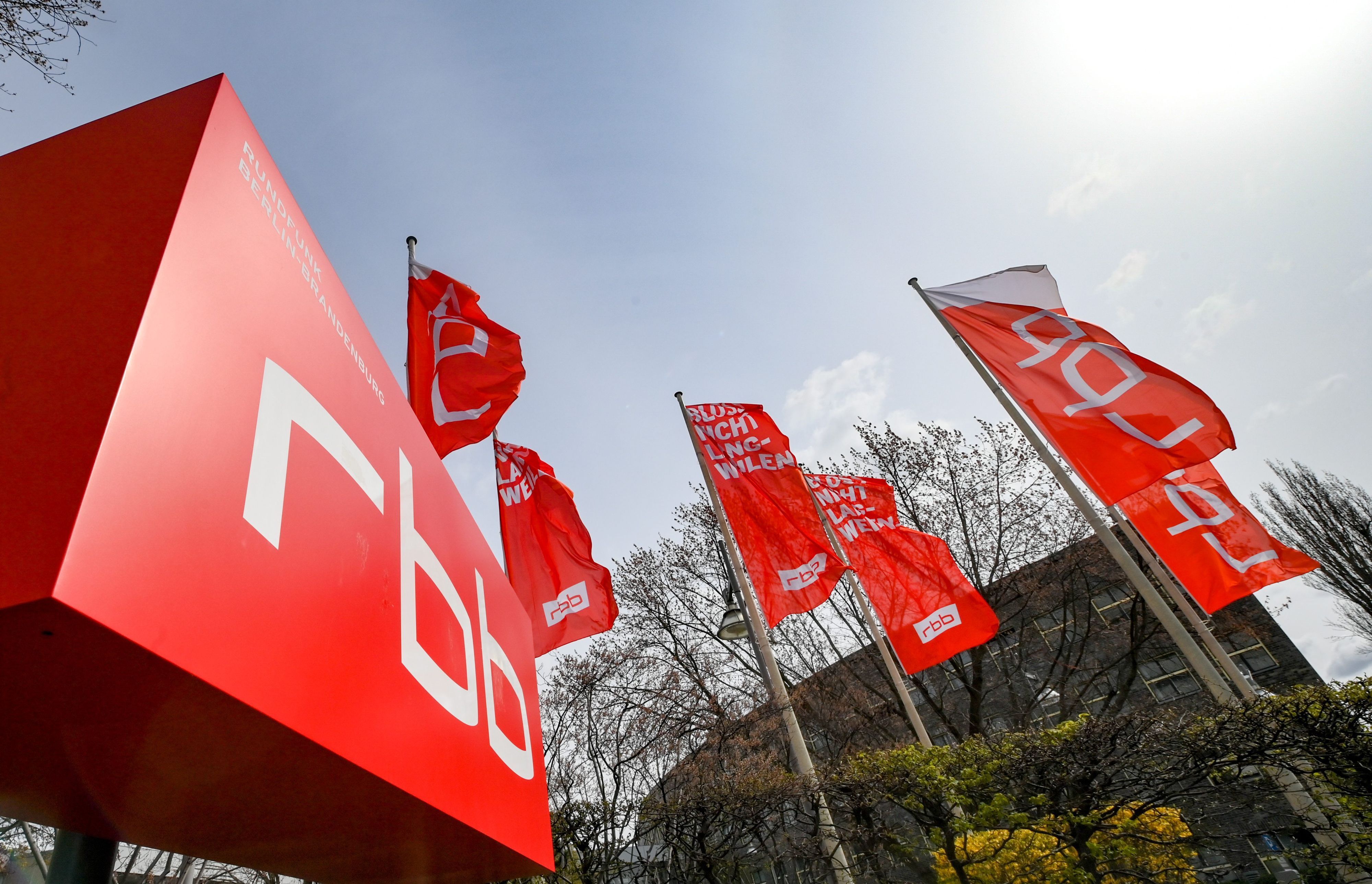 Das Logo und Fahnen des Fernsehsenders und Radiosenders Rundfunk Berlin-Brandenburg rbb am Standort Berlin Masurenallee. Das Logo ist der weiße Schriftzug „rbb“ auf rotem Hintergrund.