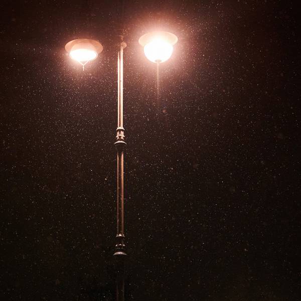 Am frühen Morgen schneit es leicht. Im Lichtschein der Laternen ist Schnee zu sehen.