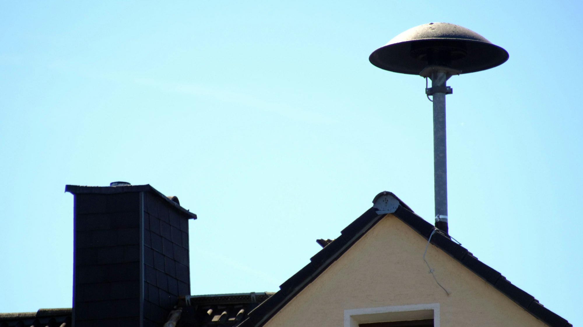 Eine Sirene ist auf einem Hausdach montiert.