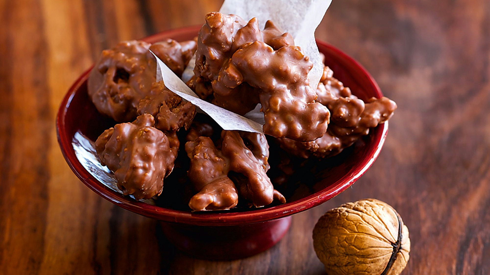 Leckere Walnuss-Amarettini-Berge (Pralinen) liegen in einer Schale, daneben ist eine Walnuss dekorativ platziert.
