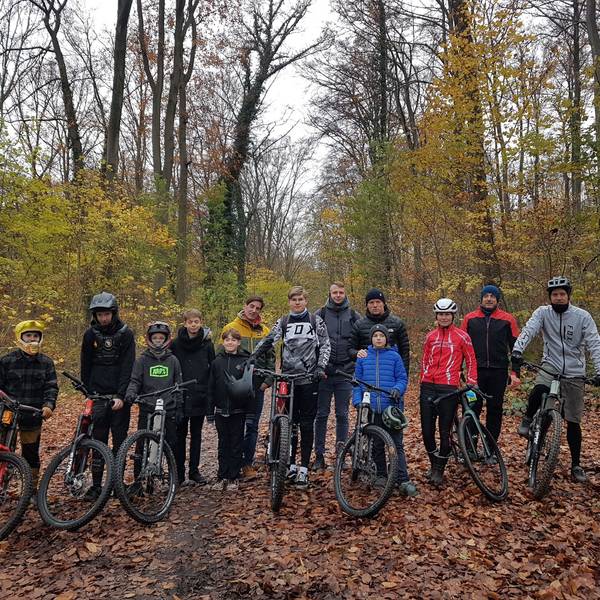Eine Gruppe Mountainbiker steht mit ihren Rädern im Wald.