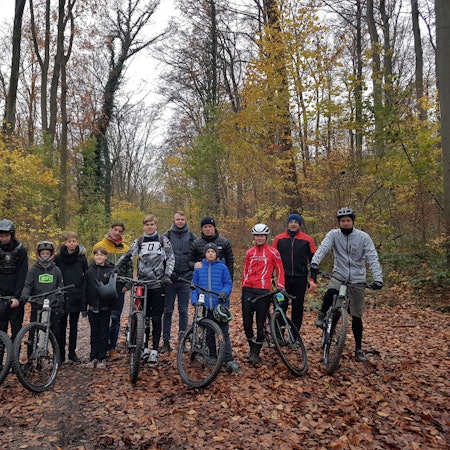 Eine Gruppe Mountainbiker steht mit ihren Rädern im Wald.