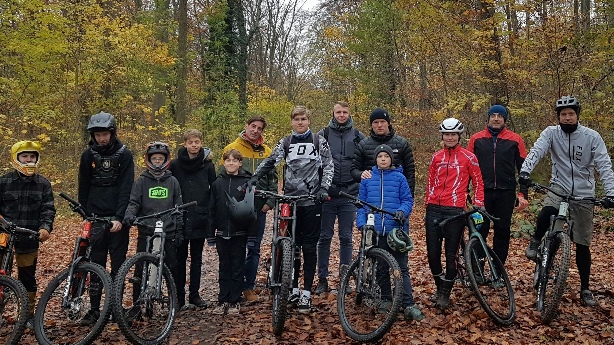 Eine Gruppe Mountainbiker steht mit ihren Rädern im Wald.