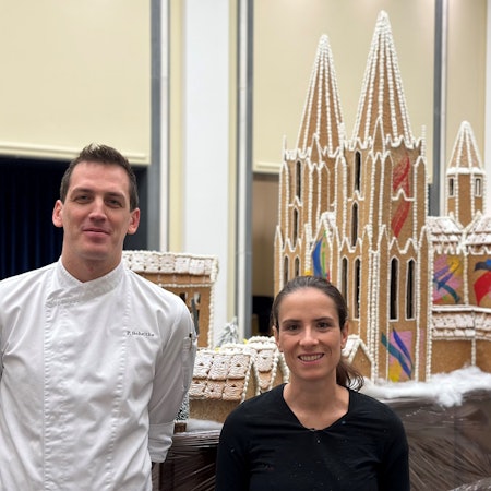 Die Graffiti-Künstlerin Mad C aka Claudia Walde und Patissier Fabian Scheithe stehen vor einem bunt bemalten Dom aus Lebkuchen.