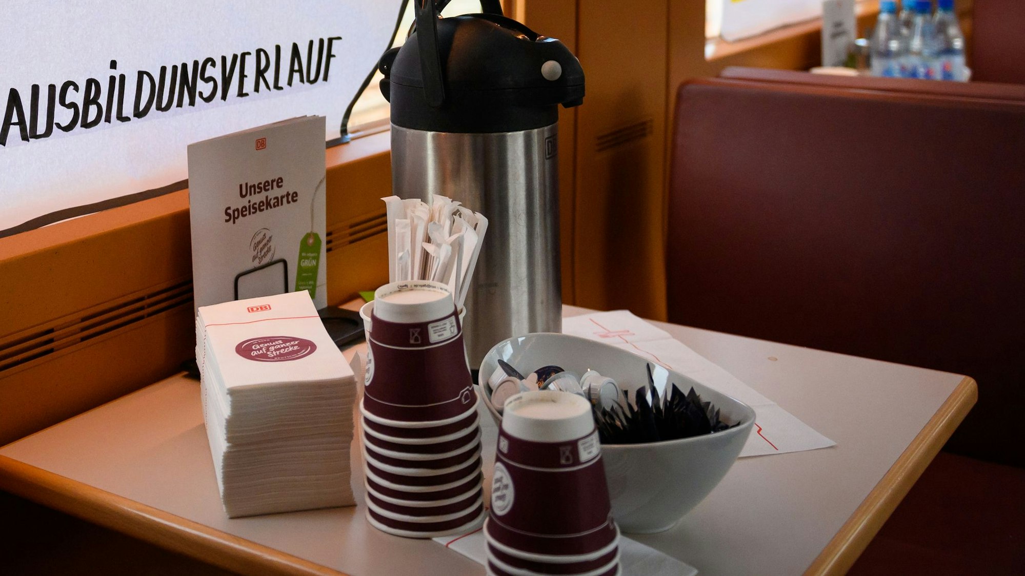 Auf einem Tisch im Bordbistro der Deutschen Bahn stehen Einwegbecher, eine Kaffee-Thermoskanne, Zuckertüten und Servietten.