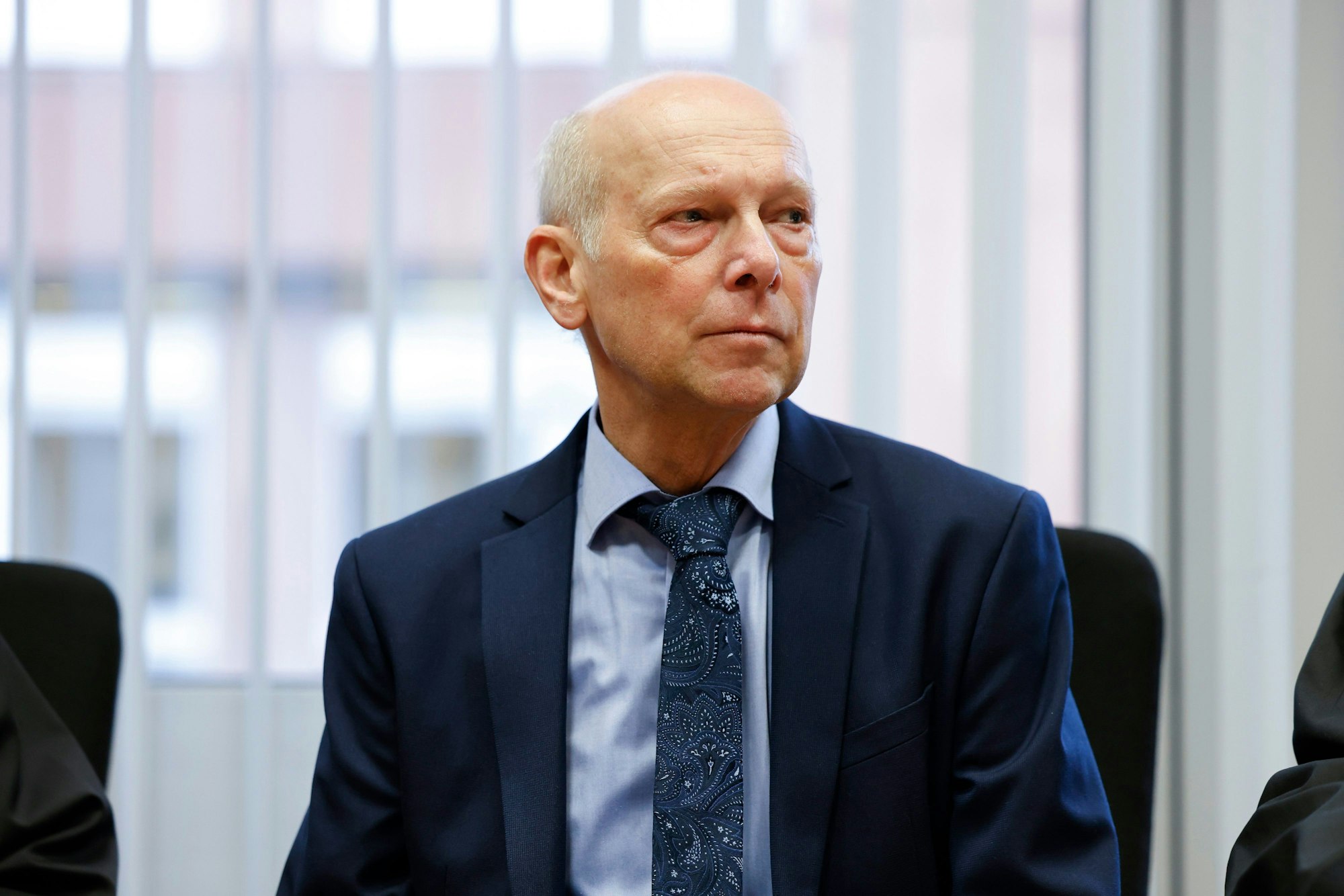 Georg Menne sitzt vor der Verhandlung im Gerichtssaal im Landgericht Köln.
