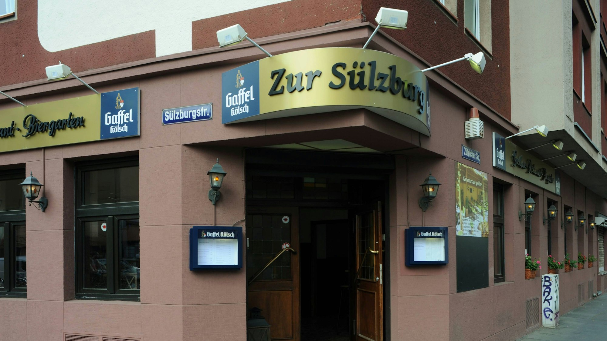Das Restaurant „Zur Sülzburg" in Köln von außen fotografiert mit dem namensgebenden Schild und der Eingangstür