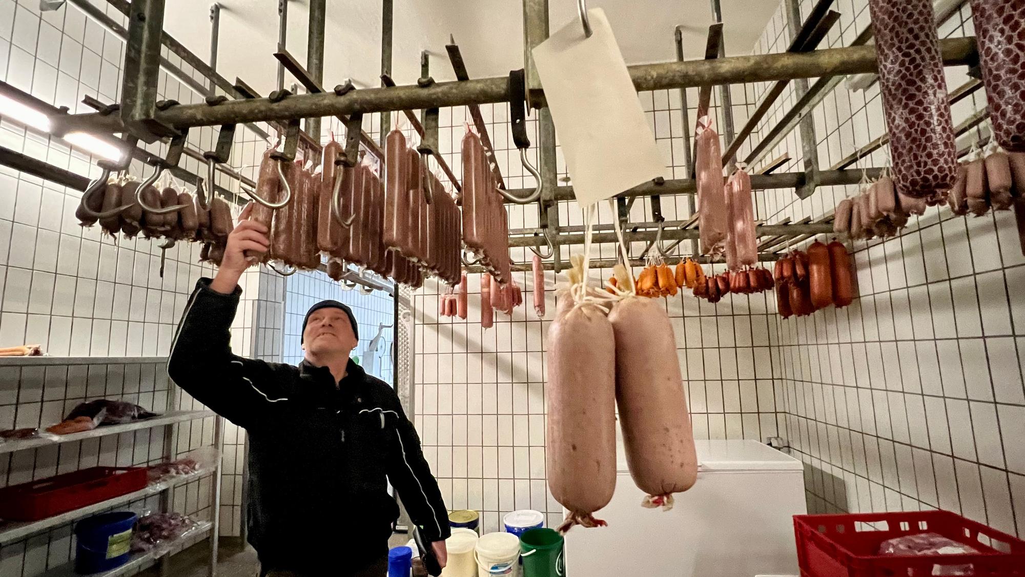 Michael Geuer im Kühlraum seiner Metzgerei mit zahlreichen Würsten.