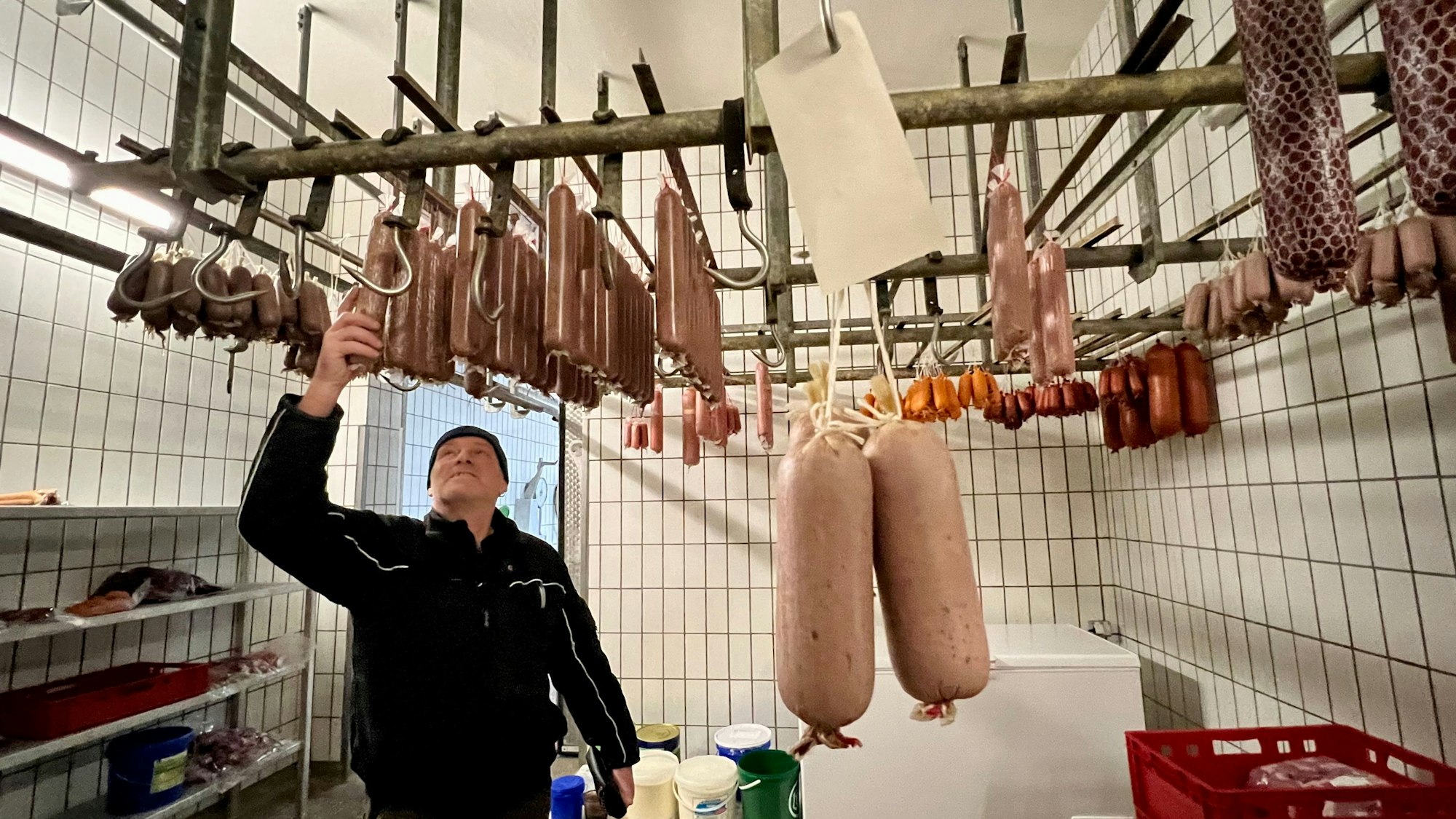 Michael Geuer im Kühlraum seiner Metzgerei mit zahlreichen Würsten.