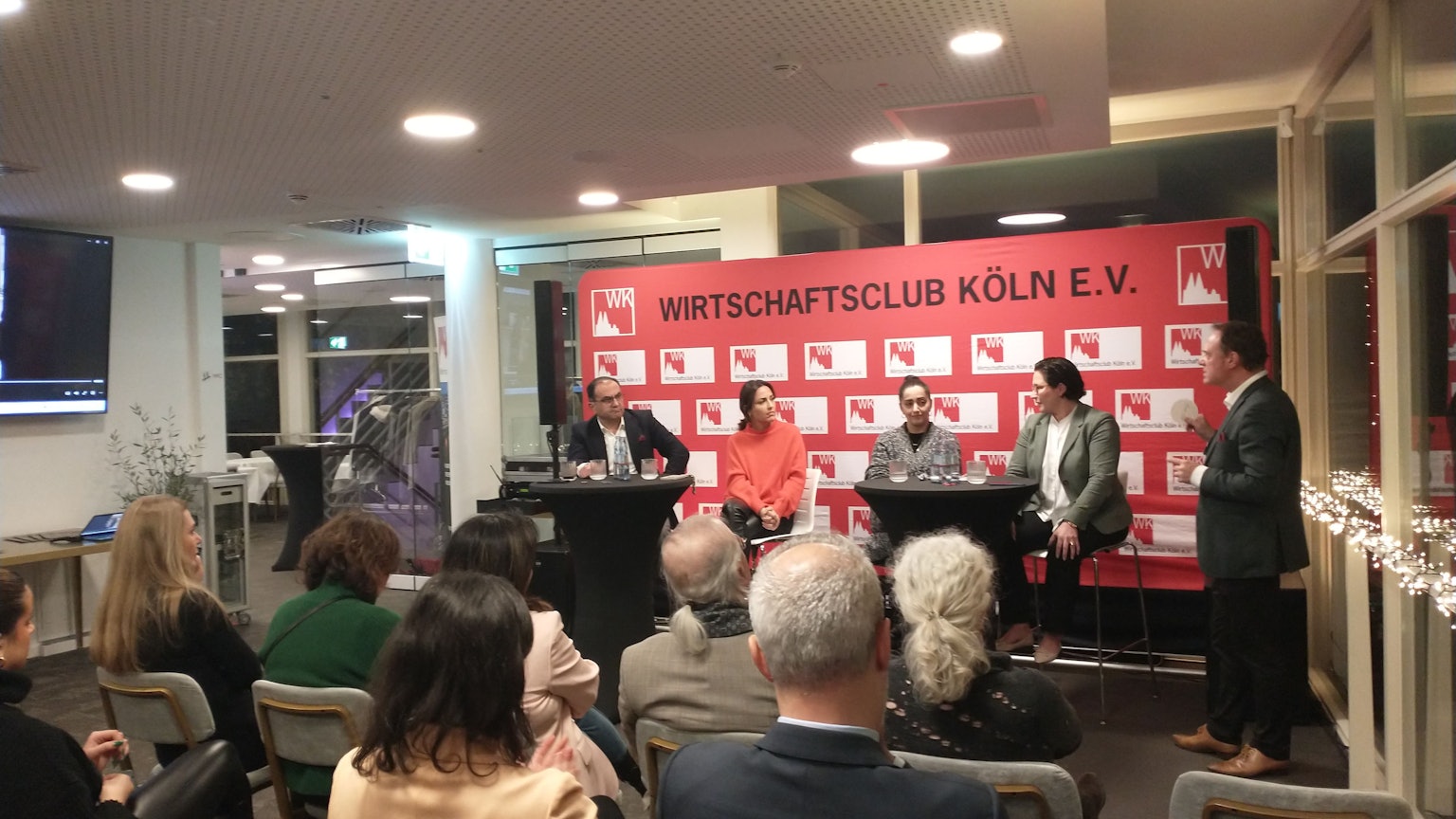 Kölner Wirtschaftsclub mit 4 Podiumsgästen und Moderator, im Vordergrund Publikum.