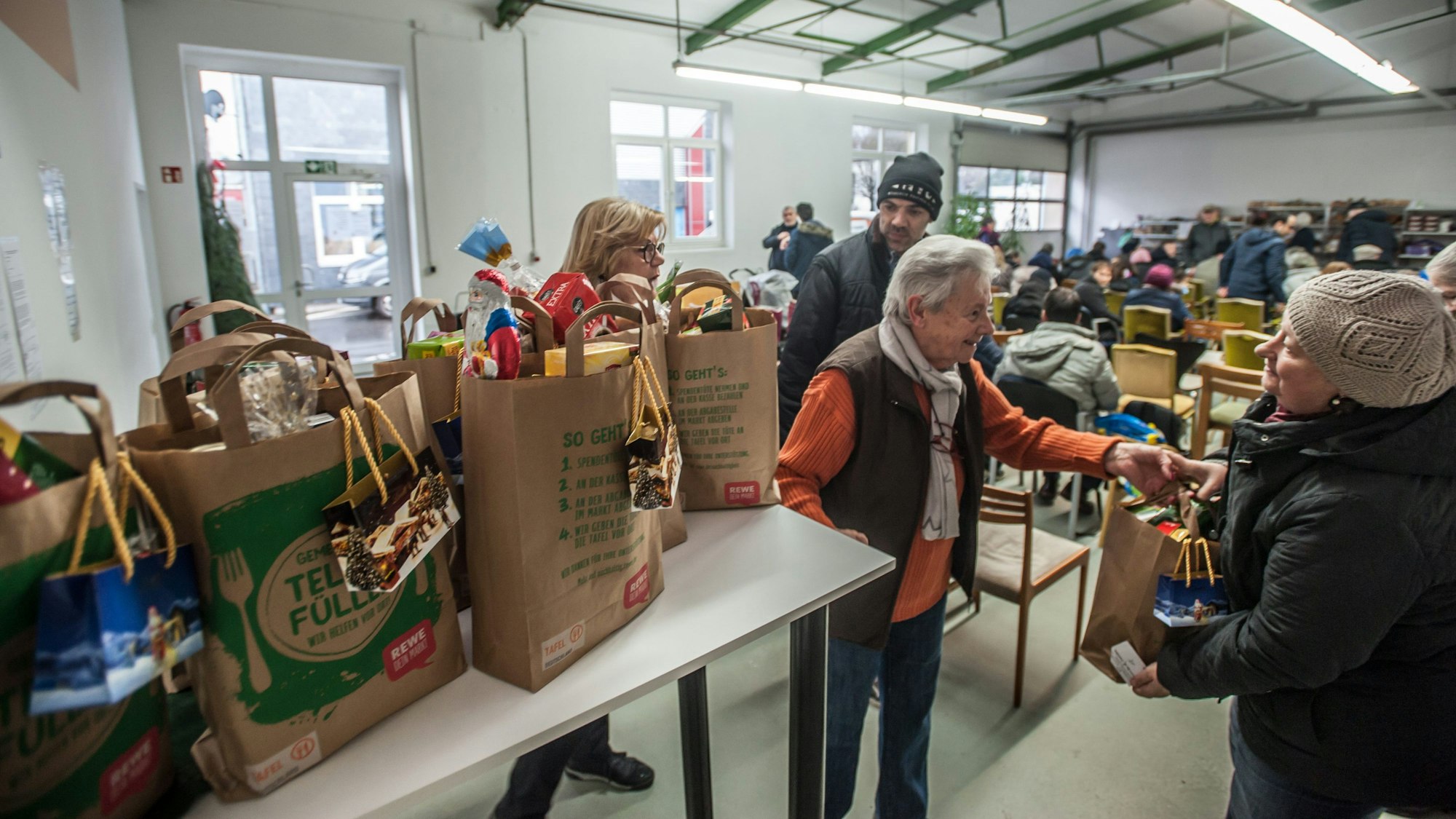 Hannelore Kretzer von der Tafel steht in der Lagerhalle und verteilt Taschen mit Lebensmitteln.