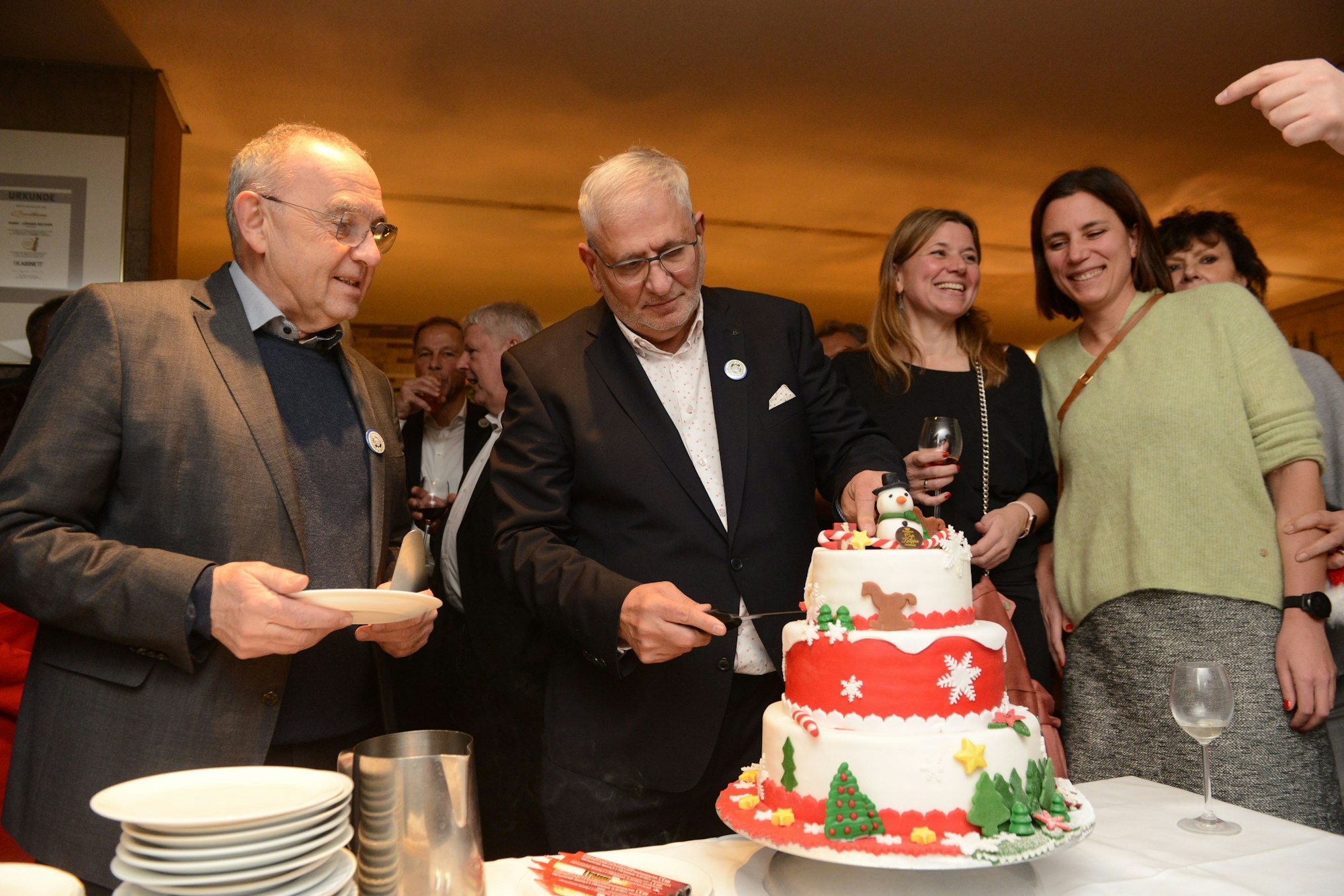 Der Gastronom Josef Rayes (Consilium, Aachener Weiher) wird am Nikolaustag 70 Jahre alt. Den Geburtstagskuchen schneidet er an mit Norbert Walter-Borjans (SPD-Bundesvorsitzender, l.) und seinen Töchtern Sina und Nadja. Die dreistöckige Torte ist weihnachtlich dekoriert.