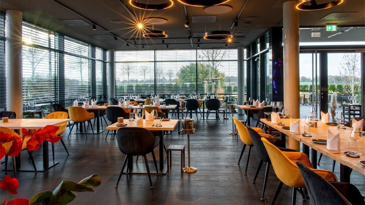 gedeckte Tische in einem Raum mit zwei großen Fensterfronten