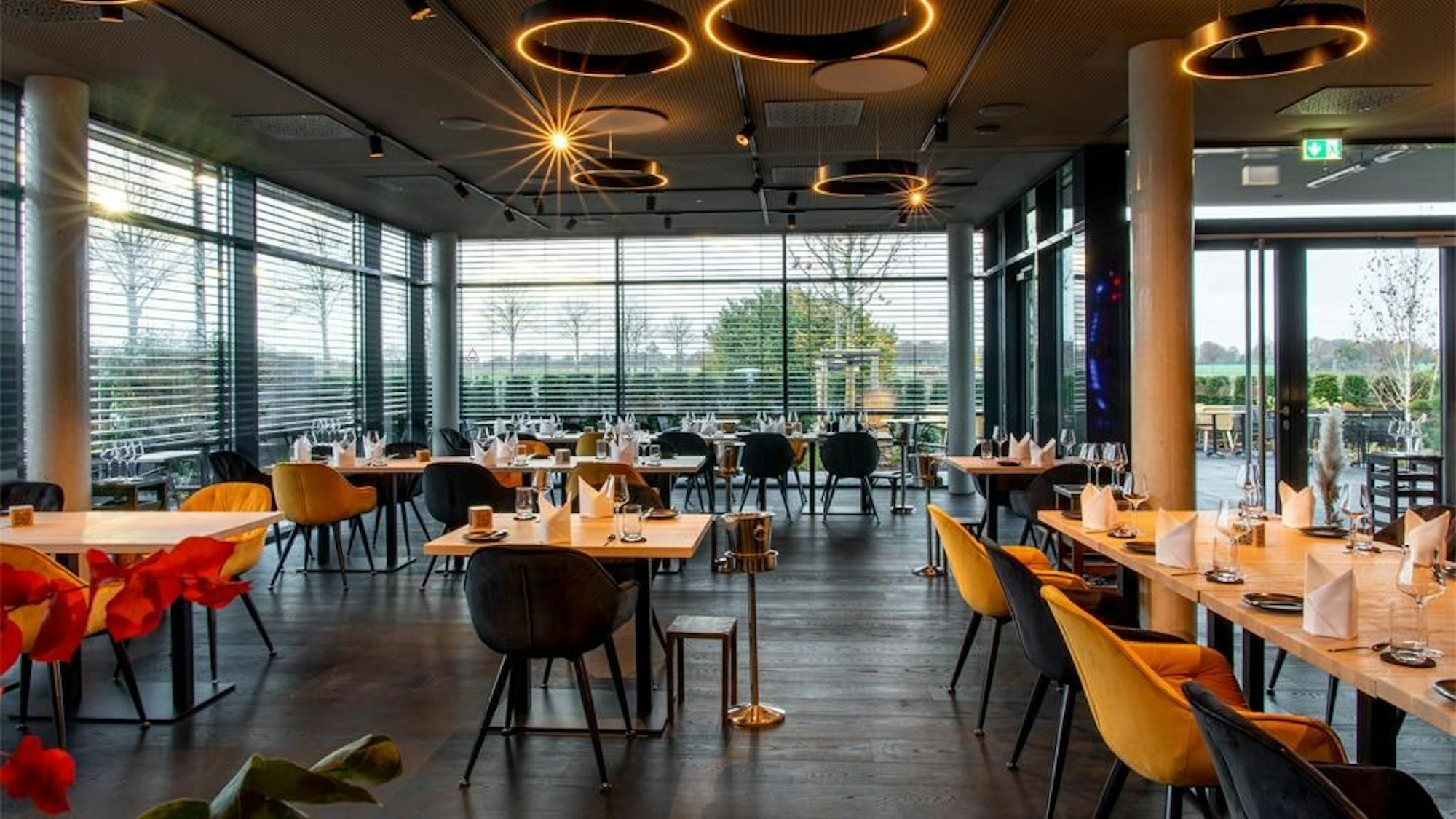 gedeckte Tische in einem Raum mit zwei großen Fensterfronten