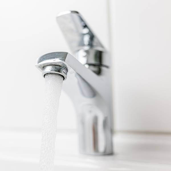 Wasser fließt aus einem Hahn in ein Waschbecken.