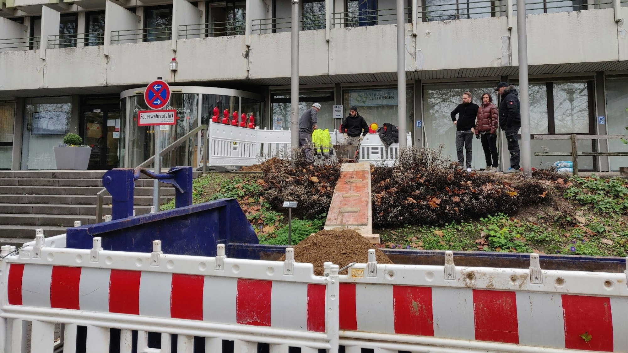 Baugitter vor dem Leichlinger Rathaus-Eingang, wo Arbeiter Erde für ein Fundament ausheben.